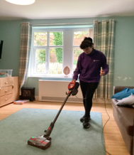 Post 16 student practicing daily living skills using a hoover